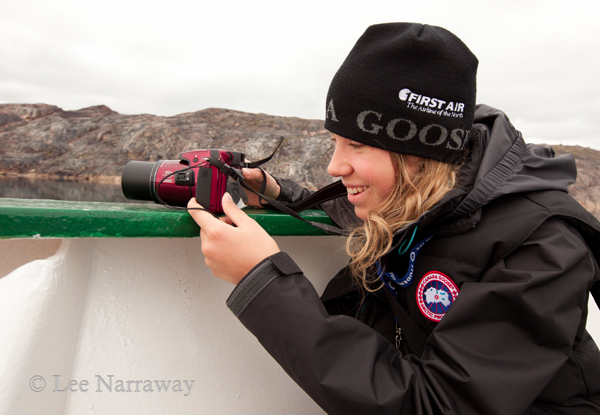 Alana Krug-Macleod holds a camera while leaning on the side of a ship during a journey with Students on Ice.
